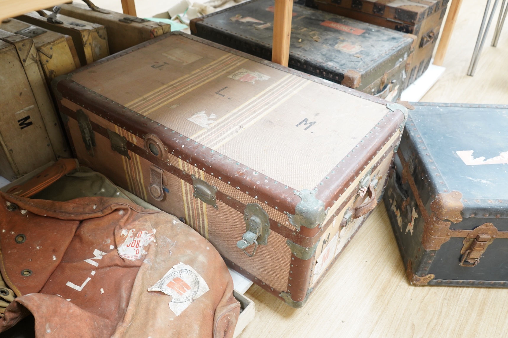 A collection of vintage luggage comprising four early 20th century bound travelling trunks and three kit bags
